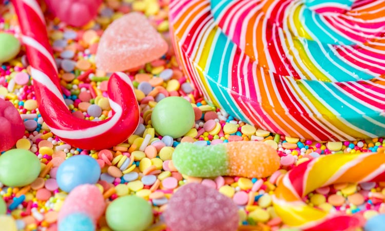Aerial view of a cluster of cavity-causing sugary candy, including a candy cane, lollipop, and gumdrops