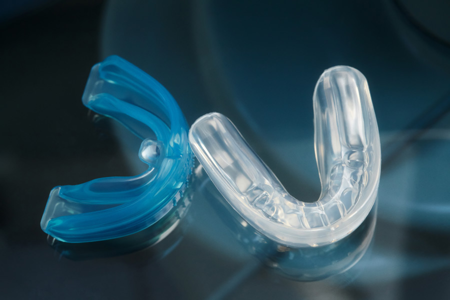 Closeup of a blue and clear mouthguard on a teal background to protect teeth during sports, and nighttime grinding and clenching