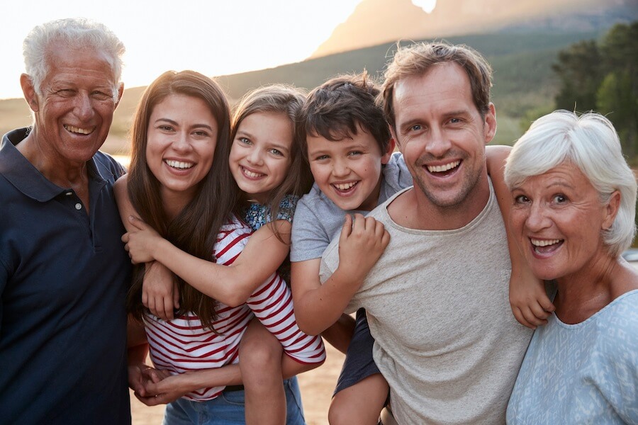 Multigenerational family photo of a mom and dad smile with their two children and a set of grandparents